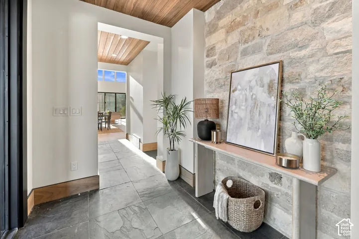 Entryway featuring large-format slate flooring, a natural stone accent wall, and wood-paneled ceilings