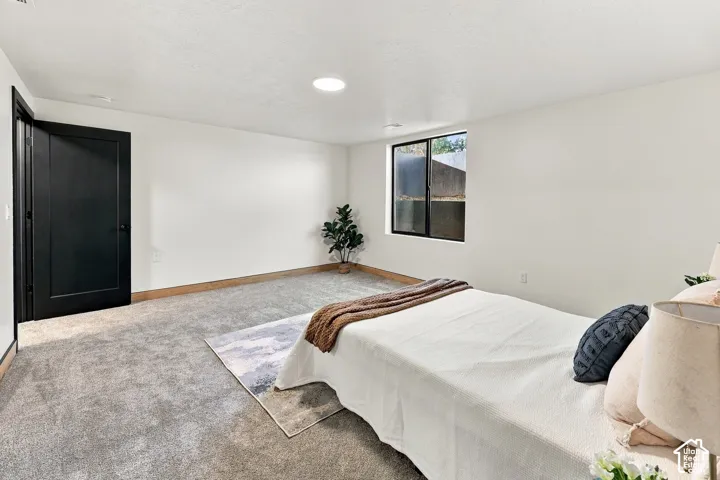 Neutral-toned carpeting, high-contrast black interior door, recessed ceiling lighting, and window with black casing