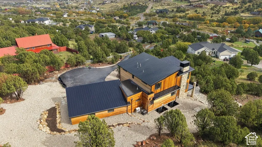 Multi-level exterior featuring natural wood siding, standing-seam metal roofing, stone-clad chimney, asphalt driveway, and gravel hardscaping