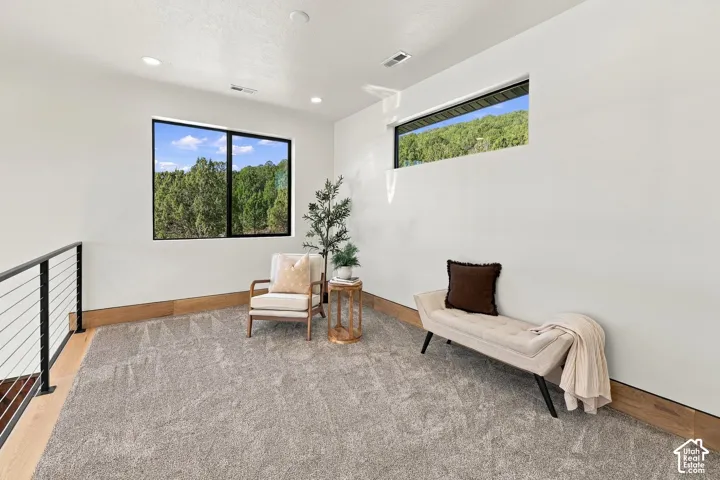Open loft with neutral-toned carpeting, wood-finish wall trim, recessed lighting, horizontal slider window, and clerestory window