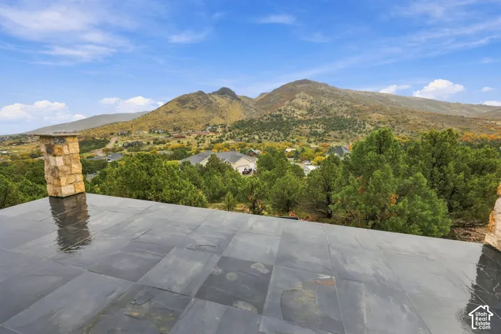 Master bedroom outdoor terrace featuring slate tile flooring, stone chimney masonry, and a mountainous landscape backdrop