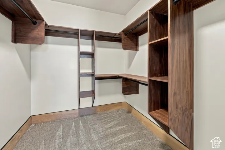 Master Ensuite walk-in closet featuring custom wood-finish built-in shelving, vertical storage towers, and black metal garment rods