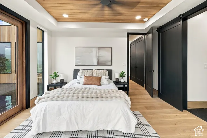 Master Bedroom with Brazilian hardwood   planking, recessed lighting, wood-finish flooring, sliding barn door with matte black hardware, and floor-to-ceiling glass door