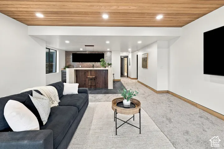 Wood-plank ceiling, recessed lighting, built-in wet bar with stone backsplash, tile flooring, and neutral wall-to-wall carpeting