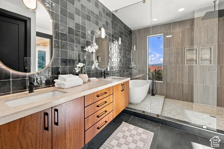 Master Ensuite with dual-vanity featuring wood-finish cabinetry, light-toned countertop, oval backlit mirrors, and matte black hardware