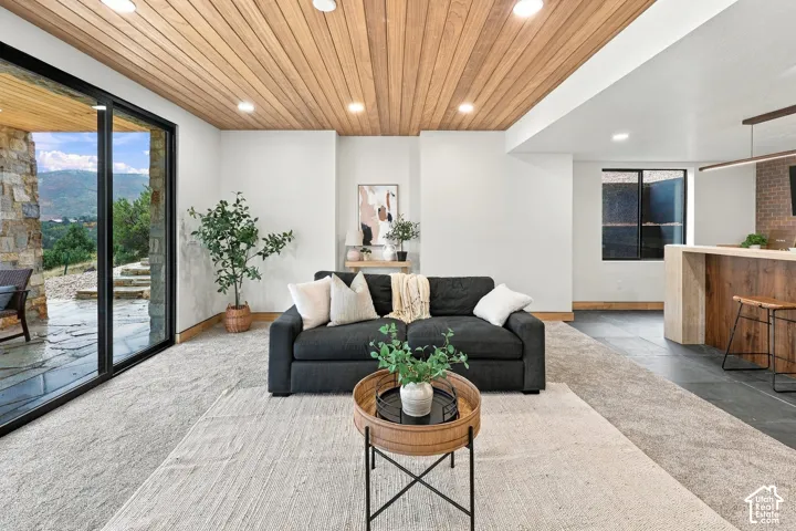 Tongue-and-groove wood-paneled ceiling, recessed lighting, floor-to-ceiling glass sliding doors, stone-accented exterior wall, and built-in bar with stone-surfaced countertop