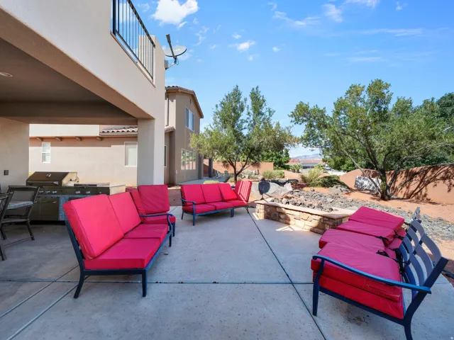 Covered patio with integrated outdoor kitchen, concrete patio, and stone fire pit surround