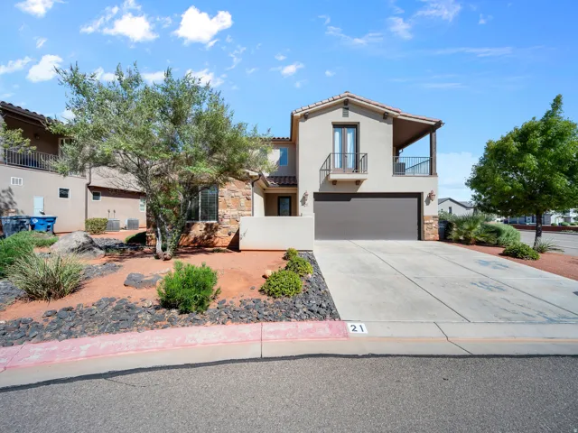 Stucco exterior with stone accents, an attached garage, a second-story balcony, and a decorative front balcony