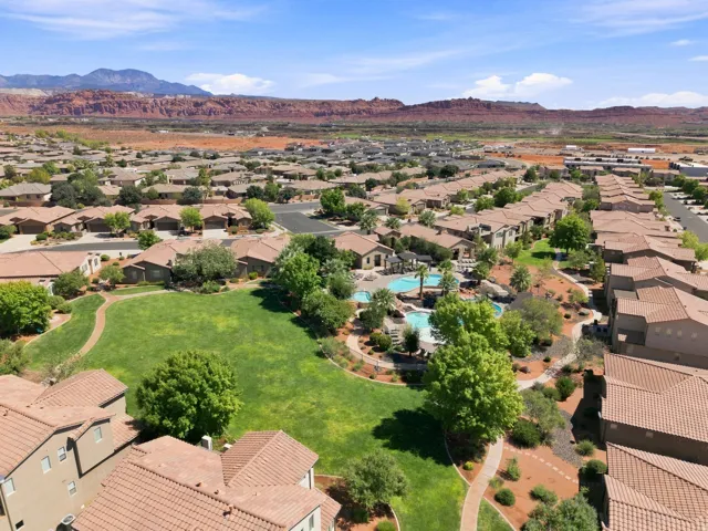 Community grounds featuring a large green space, mature trees, and a winding path