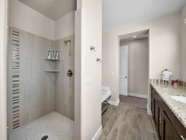 Shower with tiled walls, integrated corner shelving, and a mosaic accent strip