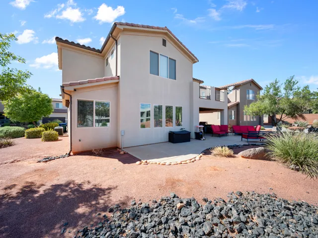 Stucco exterior with multiple windows, tile roofing, and an integrated covered patio