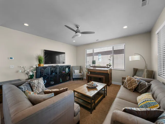 Recessed lighting, ceiling fan, multiple windows with blinds, built-in media console, and carpet flooring