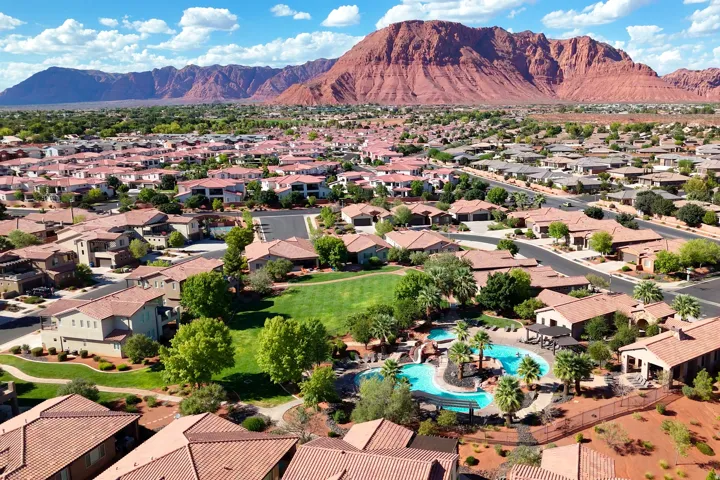 Community with extensive red-tiled roof residences, a vibrant green common area, and an integrated swimming pool with rock features