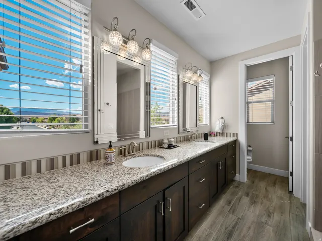 Dual vanities with undermount sinks, granite-style countertops, and dark wood-finish cabinetry