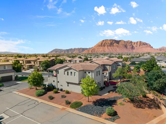 Terracotta tile roof, stucco exterior, multiple outdoor patios, mature landscaping, and prominent mountain backdrop
