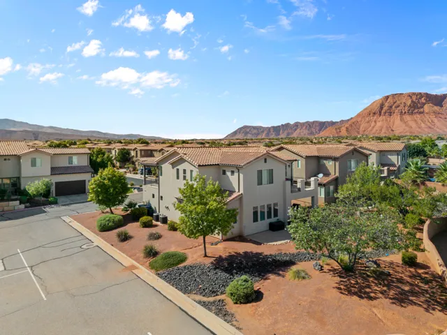 Stucco exterior with a tile roof, established landscaping, mountain backdrop, and concrete driveway