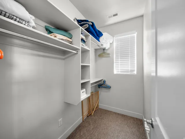 Built-in white shelving and hanging rods provide organizational options