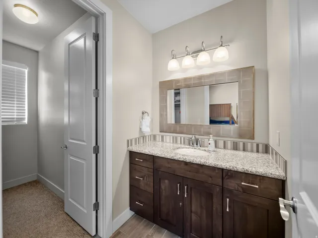 Wood-finish vanity with an integrated sink, granite countertop, and striped tile backsplash