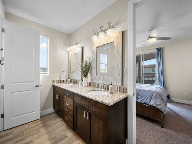 Double vanity with granite countertop, undermount sinks, and wood-finish cabinetry