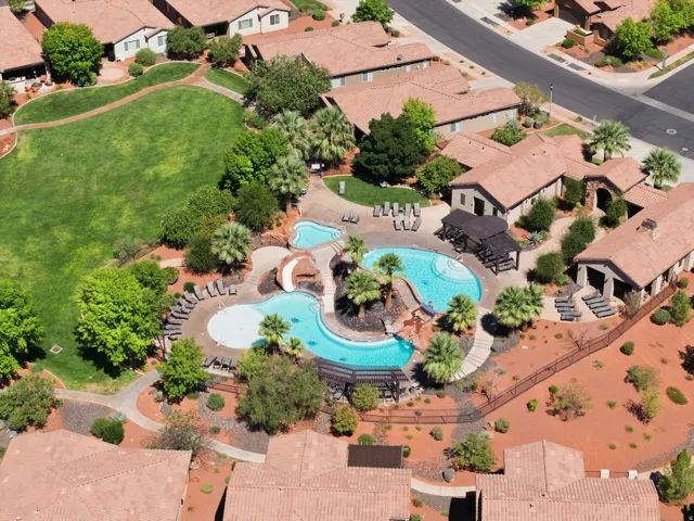Community pool with water slide, multiple lounge areas, and surrounding mature landscaping
