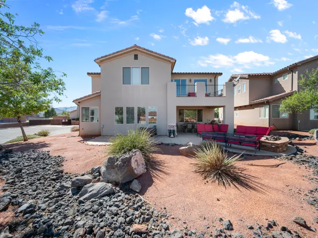 Stucco exterior with a tile roof, an upper-level balcony, a covered patio, and a built-in fire pit