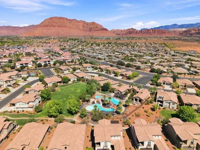 Expansive neighborhood with consistent architecture, mature landscaping, and a central green space with a community pool