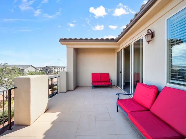 Spacious balcony with tiled flooring, stucco walls, and wrought iron railings