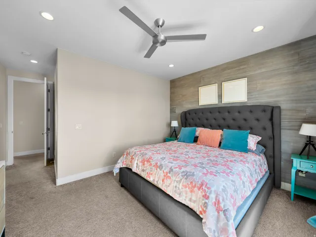 Recessed lighting, ceiling fan, accent wall with wood-finish paneling, and neutral carpet