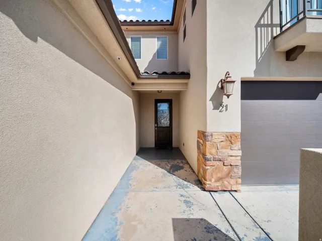 Stucco exterior with a tiled roof, stone accents, and an attached garage