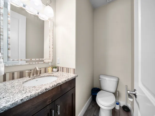 Wood-finish flooring with a white toilet and a dark wood vanity
