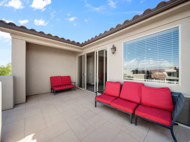 Expansive exterior balcony featuring large format tile flooring, stucco walls, and a sliding glass door
