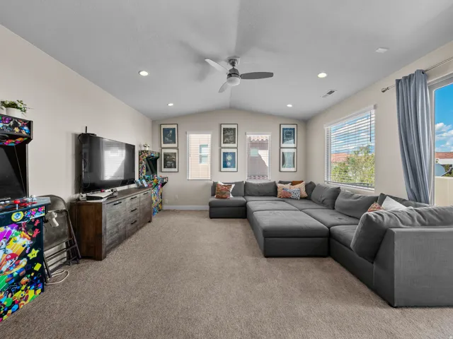 Carpeted room with a vaulted ceiling, recessed lighting, and a ceiling fan
