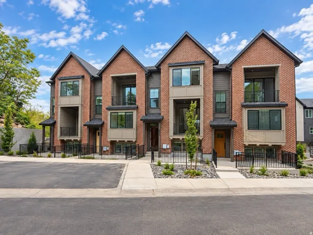 Brick and siding exterior with multiple balconies, contemporary black-framed windows, and manicured landscaping