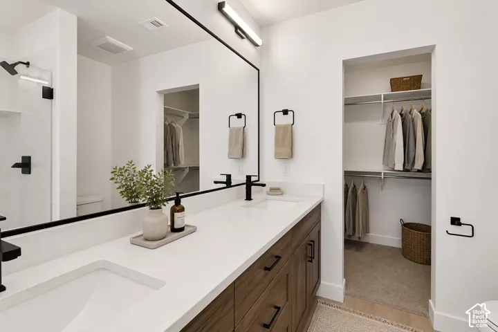 Dual vanity with integrated sinks, wood-finish cabinetry, and matte black fixtures