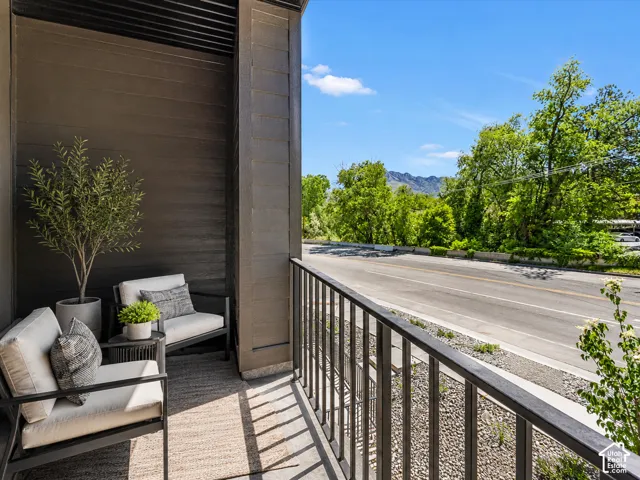 Private balcony with dark wood-finish siding, metal railing, and an outdoor rug