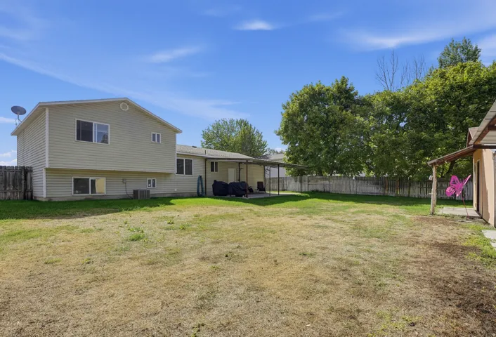 Expansive backyard featuring a covered patio, a detached shed, a full perimeter fence, and mature trees