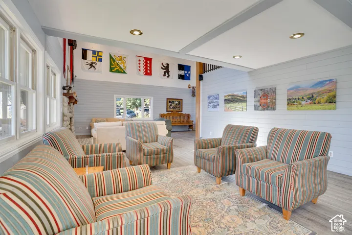 Vaulted ceilings, horizontal plank wall paneling, recessed lighting, stone fireplace surround, and wood-finish flooring