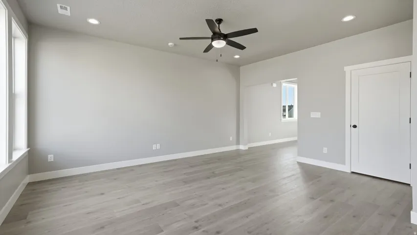 Vaulted ceiling, recessed lighting, wood-finish flooring, ceiling fan, and white trim