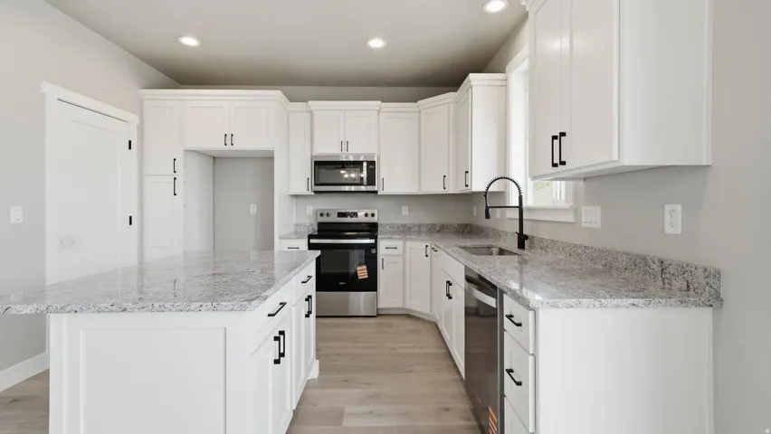 Kitchen featuring a central island with countertop seating, white shaker-style cabinetry, stainless steel appliances, and light wood-finish flooring