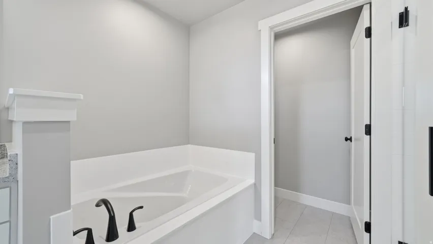 Built-in soaking tub with matte black fixtures, white trim, and light-toned wall paint