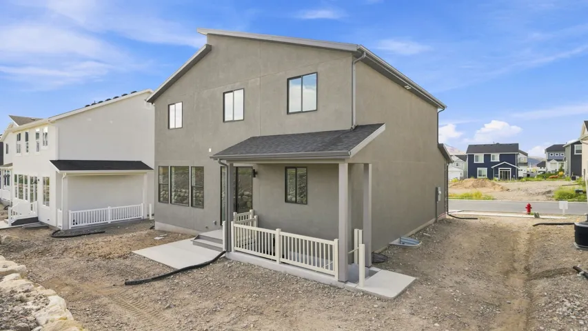 Contemporary stucco exterior with a covered patio, multiple windows, and a dark shingle roof