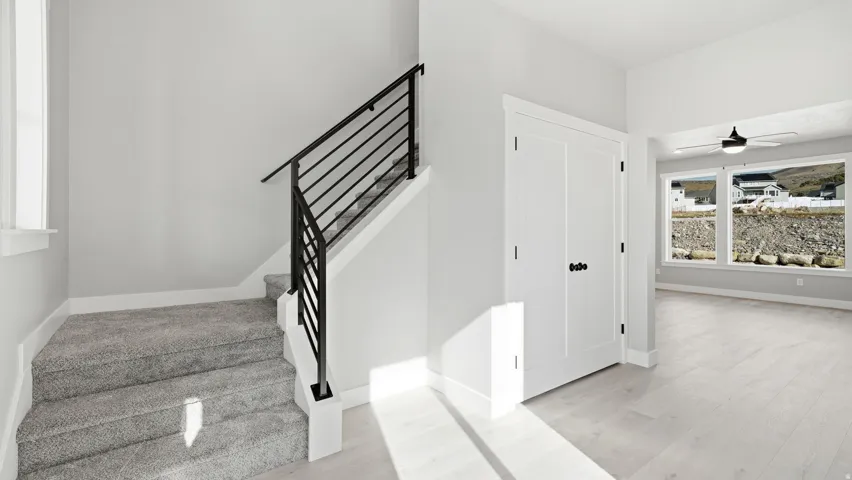 Modern interior featuring light wood-finish flooring, a contemporary staircase with black metal railing, and white two-panel doors