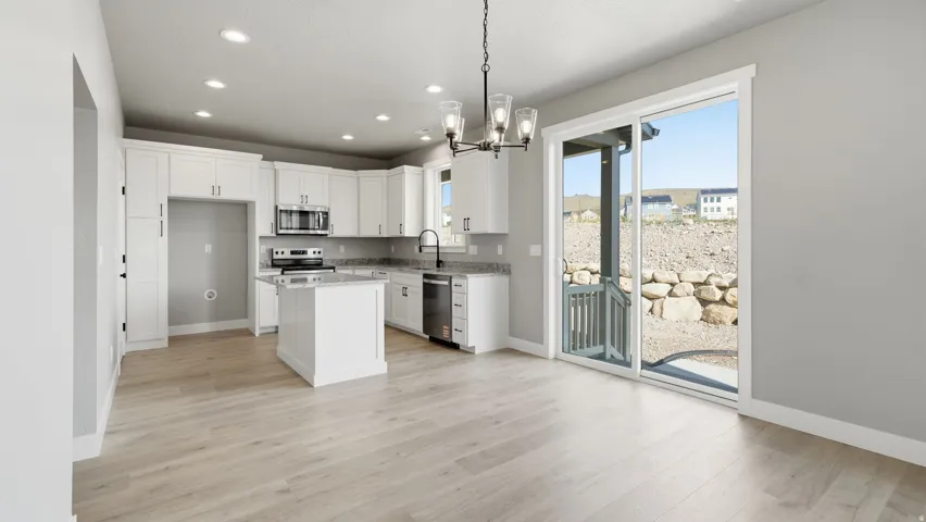 White cabinetry, light wood-finish flooring, recessed lighting, and a sliding glass door