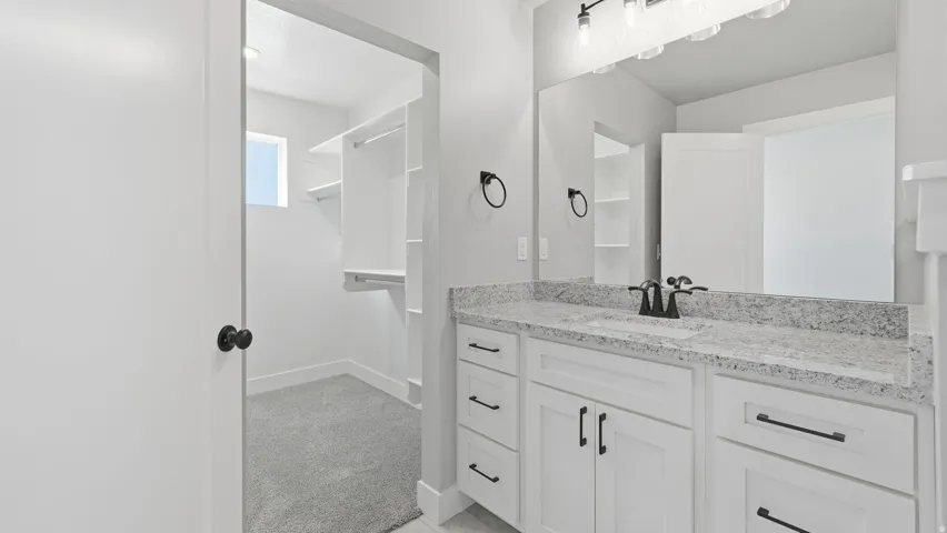 White vanity with a stone-finish countertop, single undermount sink, and matte black fixtures