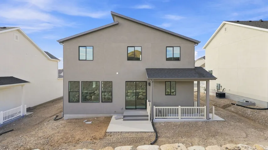 Rear exterior featuring a covered patio with white railing, sliding glass door access, and a concrete patio
