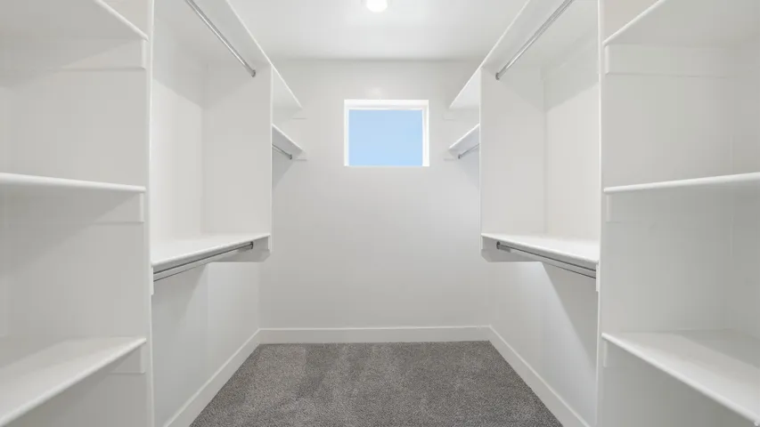 Built-in white shelving and hanging rods, recessed ceiling lighting, and a window