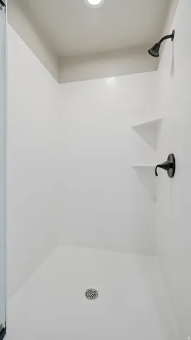 Shower enclosure with white tile walls, recessed lighting, and matte black fixtures