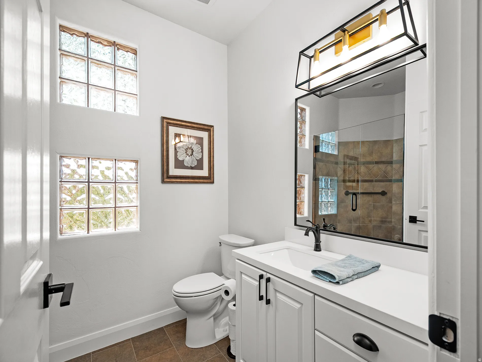 White shaker-style vanity with a solid surface countertop and undermount sink