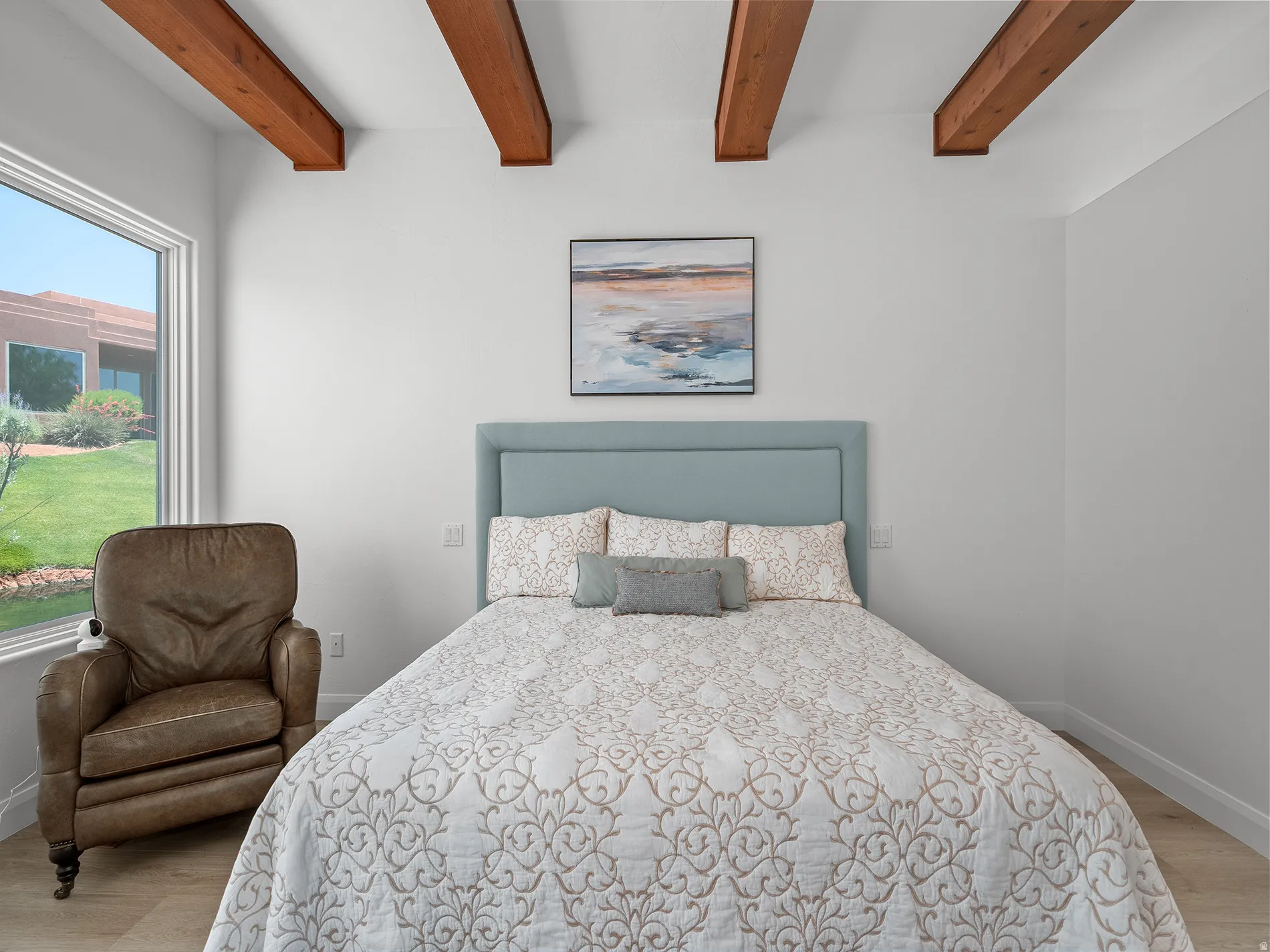Wood-finish flooring, exposed ceiling beams, and a large window