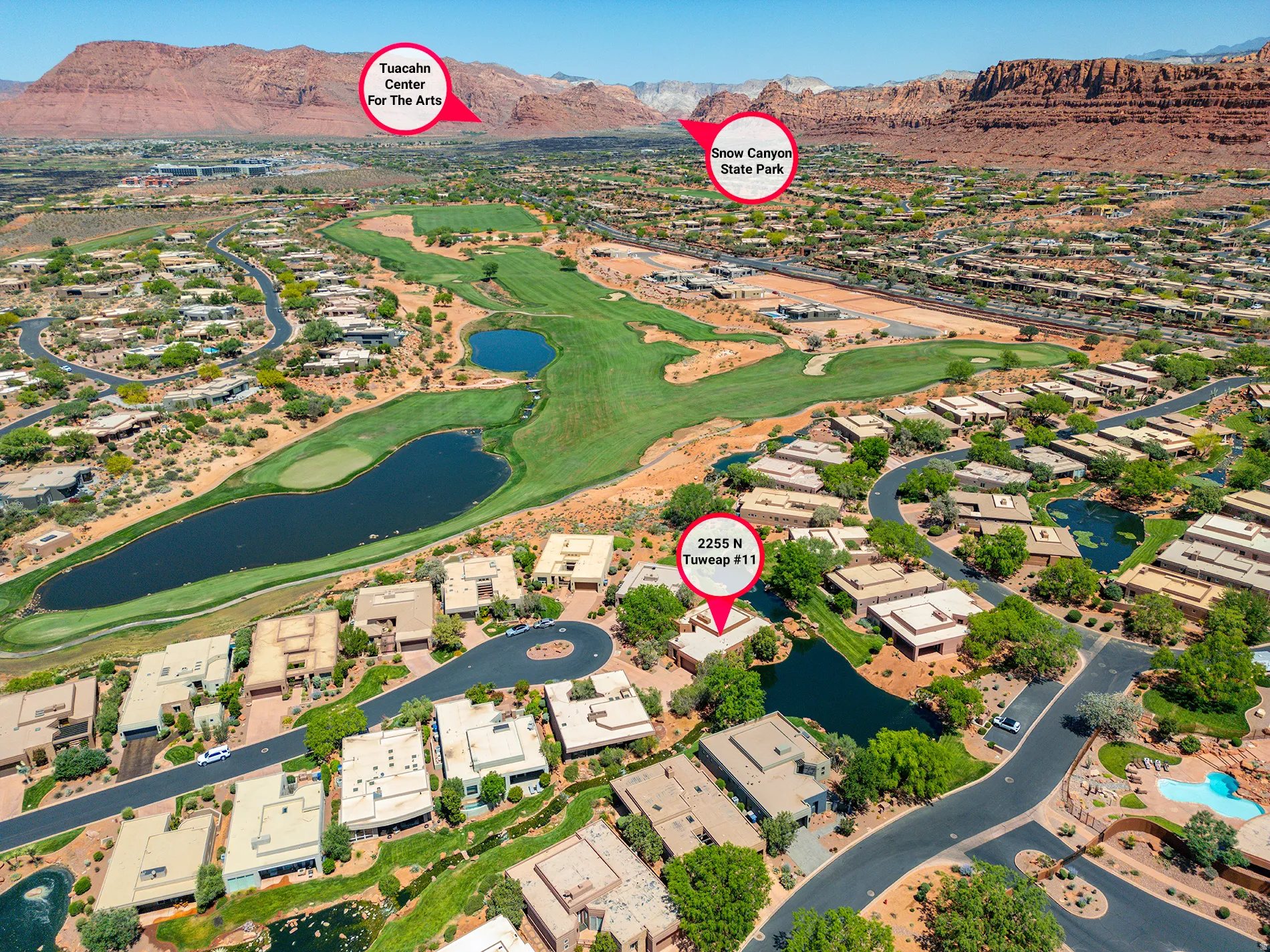 Aerial perspective showcasing residential properties, a golf course with water features, and expansive desert terrain